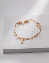 Minimalist gold bracelet with pearls on a white surface