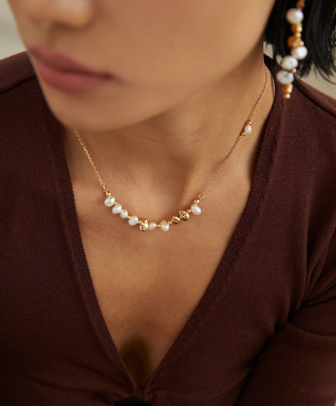 Pearl necklace worn by a person in a brown top
