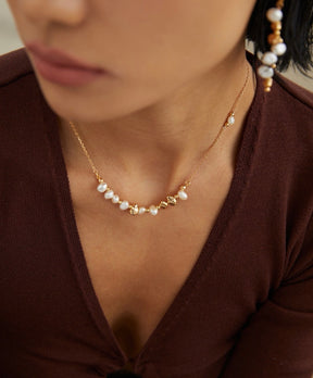 Pearl necklace worn by a person in a brown top