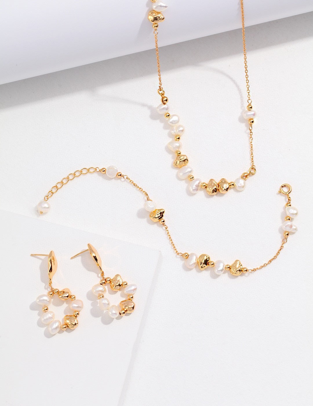 Gold and pearl jewelry set including necklace, bracelet, and earrings on a white background