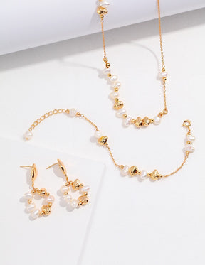 Gold and pearl jewelry set including necklace, bracelet, and earrings on a white background