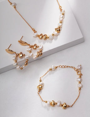 Gold and pearl jewelry set, including necklace, earrings, and bracelet on a light gray background
