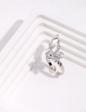 Silver ring with a butterfly design and blue gemstone on a white background