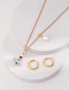 Gold necklace and earrings on a white surface. Detachable earrings into pendants.