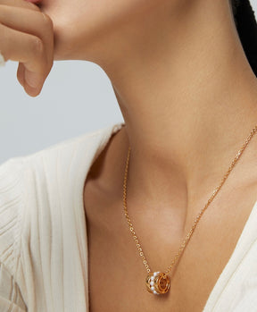 Gold necklace with a pendant worn by a person against a neutral background