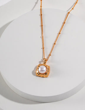 Gold necklace with a pearl pendant on a white background