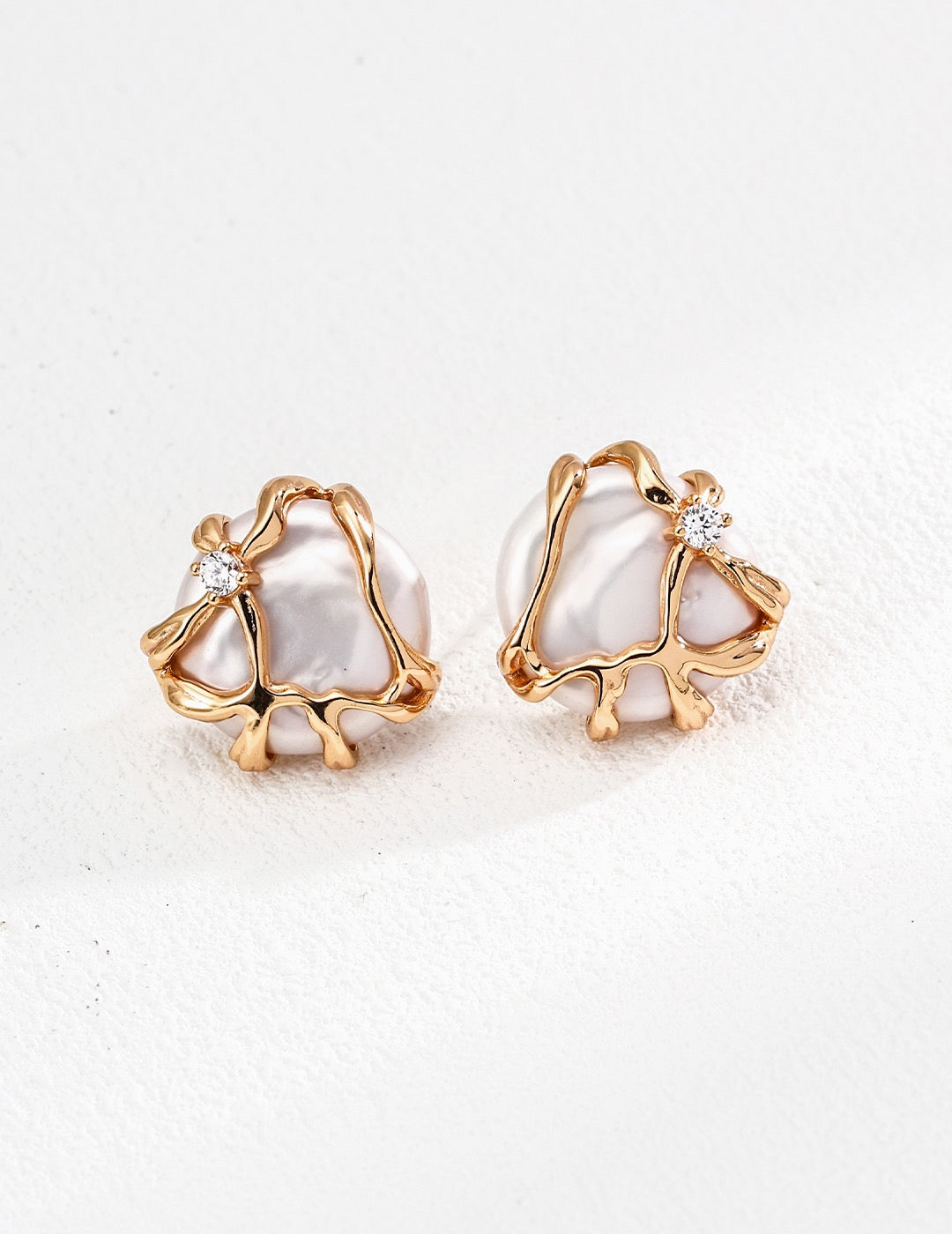 A pair of baroque pearl earrings with gold frames and zircon accents, displayed against a white background.
