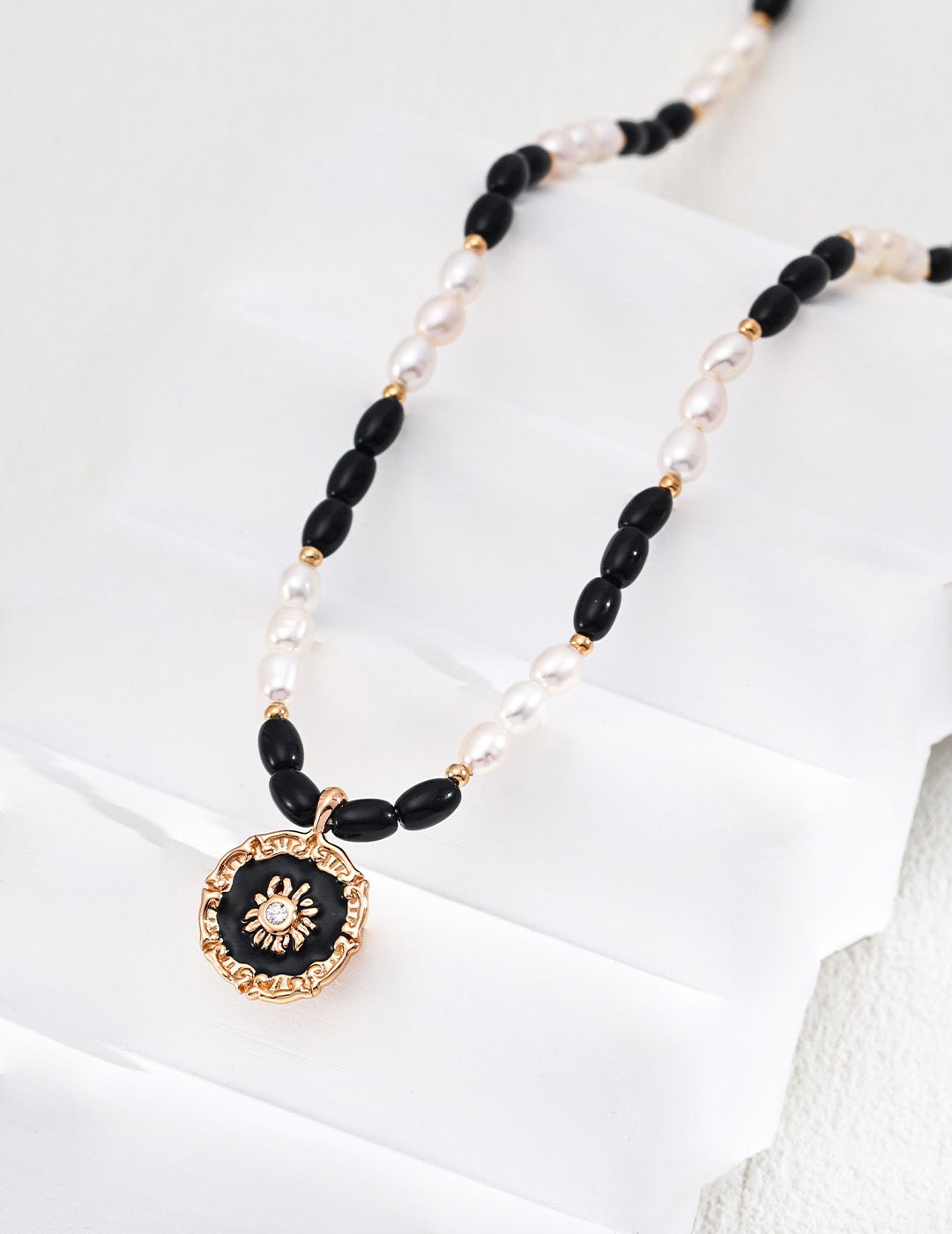 Necklace with black and gold pendant on a white background