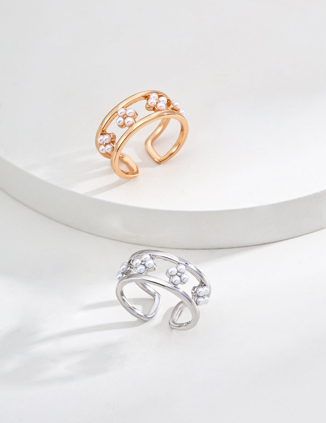 Gold and silver adjustable open rings featuring a floral design with delicate freshwater pearls, displayed on a minimalist white background.