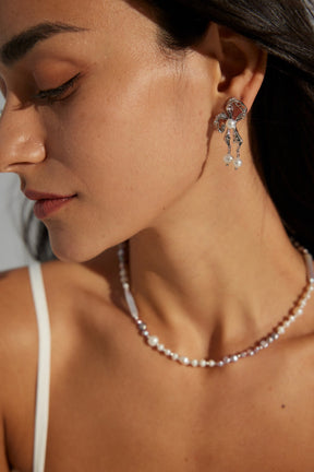 A woman wearing a pair of butterfly-shaped pearl earrings attached to a post, crafted in 18K gold vermeil and sterling silver.