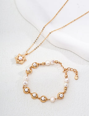 Gold necklace and bracelet set with pearls on a white background