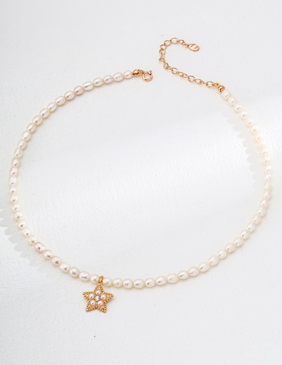 Pearl necklace with a gold star pendant on a white background