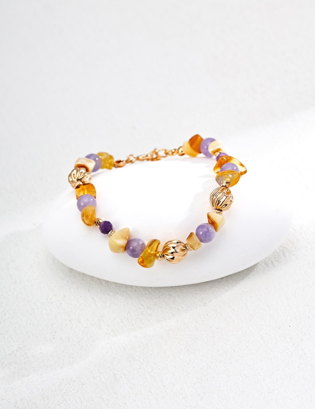 Bracelet with gold and multicolored gemstones on a white surface