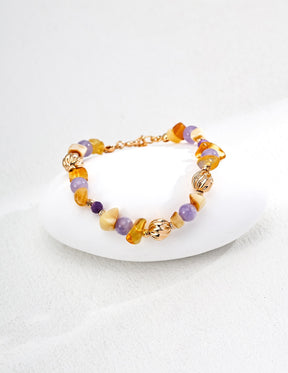 Bracelet with gold and multicolored gemstones on a white surface