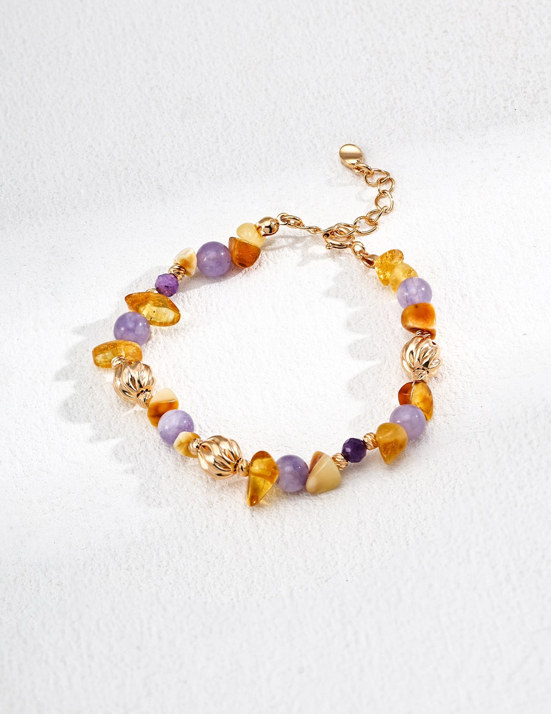 Multicolored gemstone beaded bracelet with gold accents on a white background