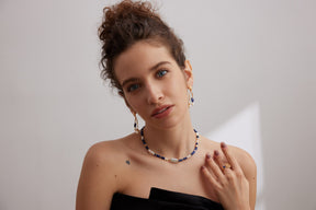 Woman wearing a necklace and earrings against a plain background
