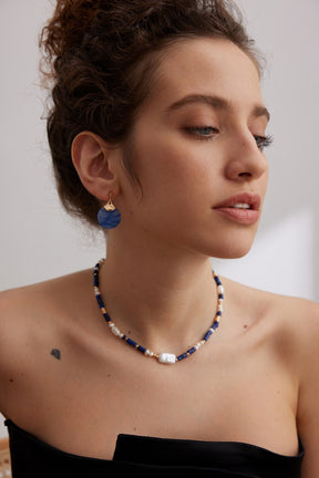 A woman wearing a matching necklace and earrings with a neutral background