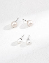 Set of pearl earrings on a textured white surface