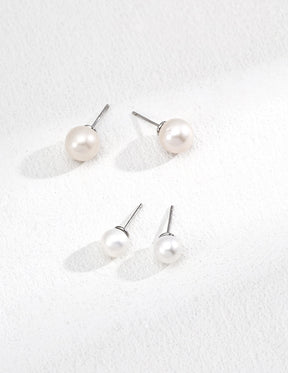 Set of pearl earrings on a textured white surface