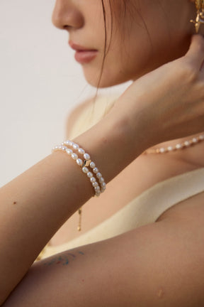 Close-up of a person wearing pearl jewelry on a plain background