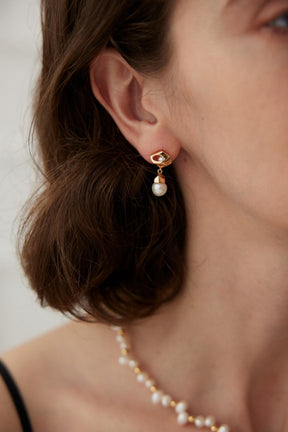 A close-up of a lady wearing a gold vermeil earring with the Freshwater Pearl Drop.