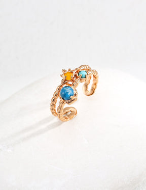 Gold ring with blue and yellow gemstones on a white background
