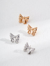 Bow-shaped earrings in rose gold and silver on a white background