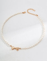 Freshwater pearl necklace with 18K gold vermeil bow pendant and clasp on gray background