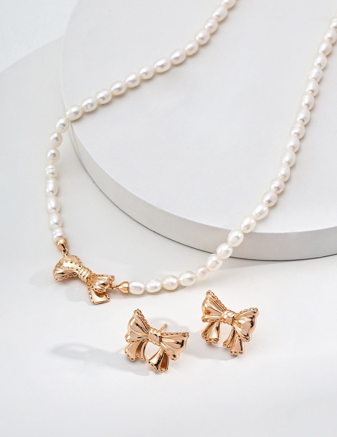Pearl necklace with gold bow pendants on a white background