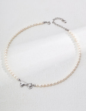 Pearl anklet with a silver bow charm on a light gray background