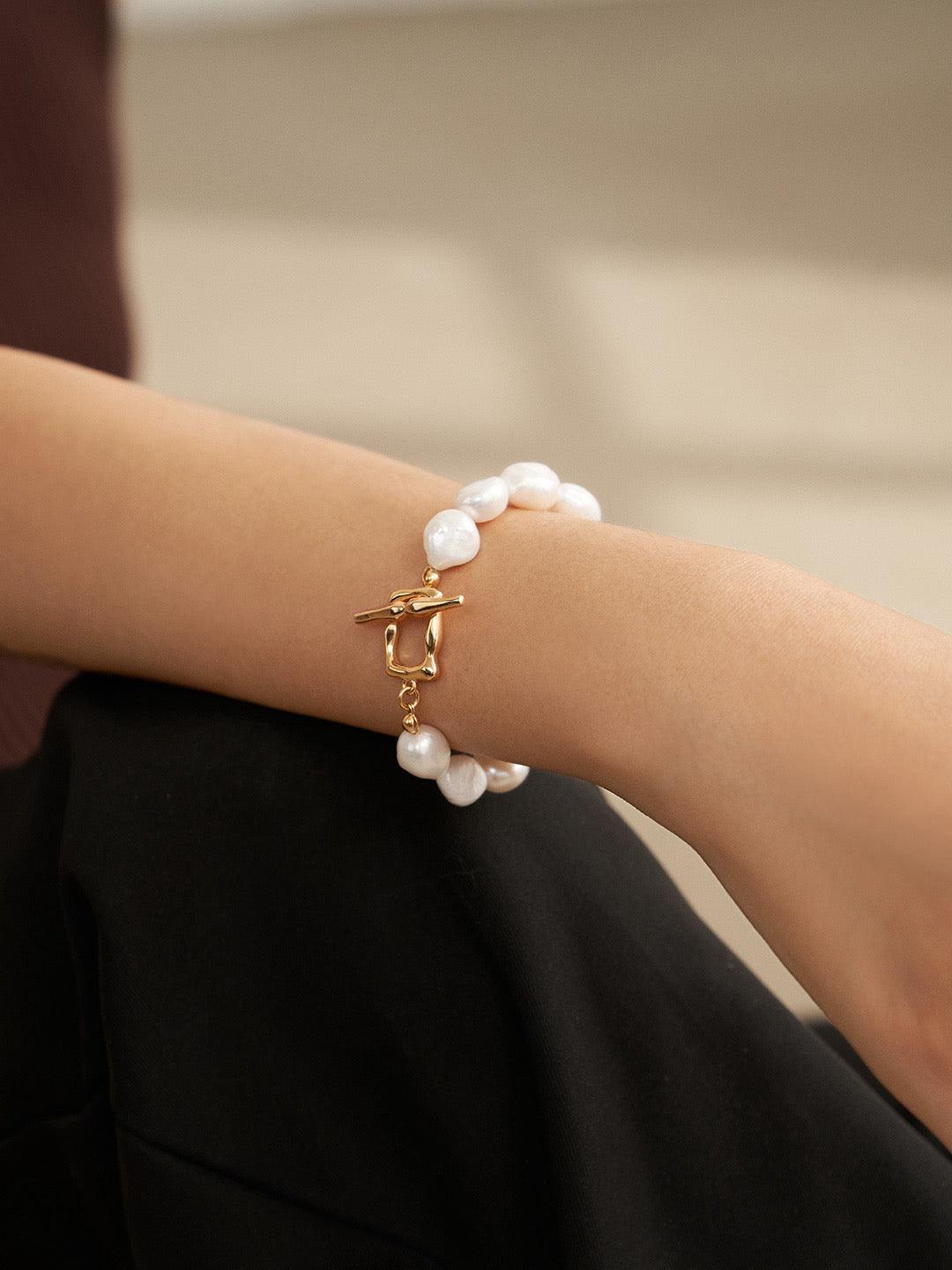 A person is wearing a large baroque bracelet with an elegant old vermeil toggle closure on their wrist.