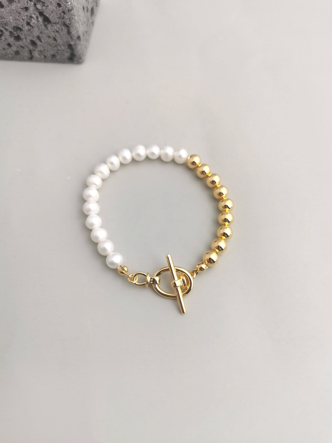 lustrous 6mm freshwater pearls with gleaming 18K gold vermeil beads in perfect symmetry displayed on the grey background.