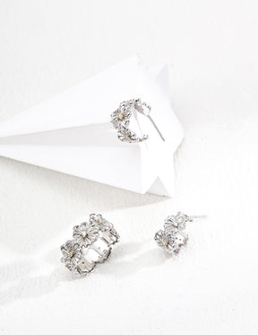 Silver daisy hoop earrings and a daisy silver cuff ring on a white background
