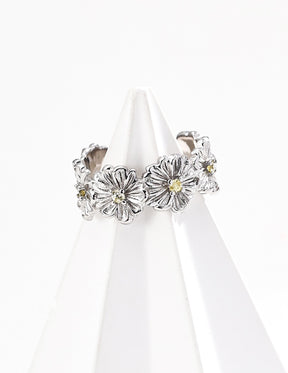 A silver floral cuff ring on a white stand