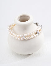 Pearl bracelet on a white ceramic vase with a white background