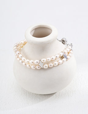 Pearl bracelet on a white ceramic vase with a white background