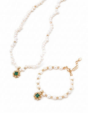 Pearl necklace and bracelet set with green gemstones on a white background