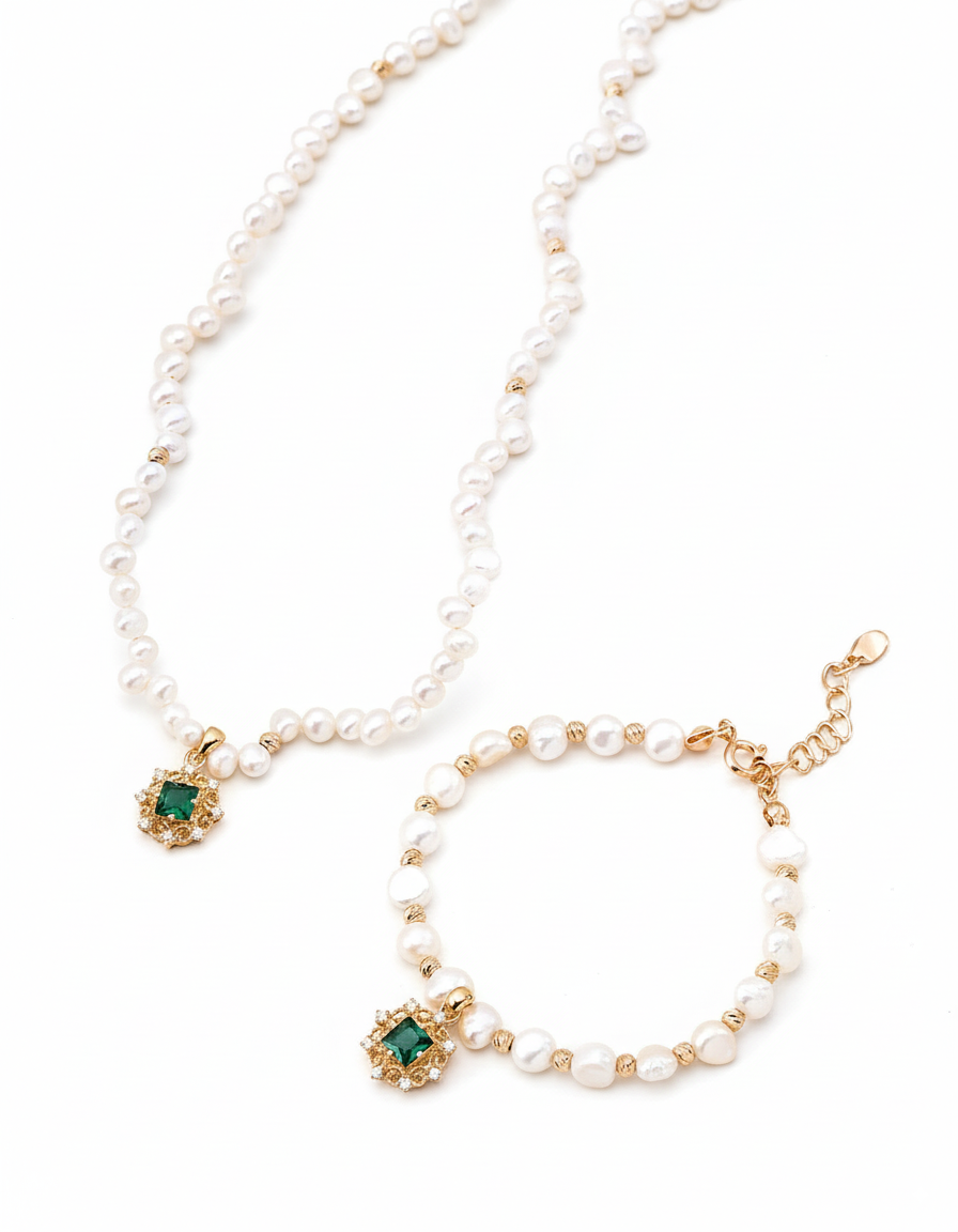 Pearl necklace and bracelet set with green gemstones on a white background