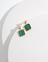 Gold earrings with green square malachite stones on a white background