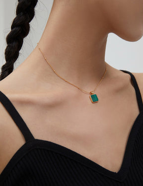 Necklace with a green malachite pendant on a model against a neutral background