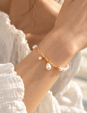 Ethereal Knot pearl bracelet on a model's wrist, showing the 18K gold vermeil knot and dangling freshwater pearl