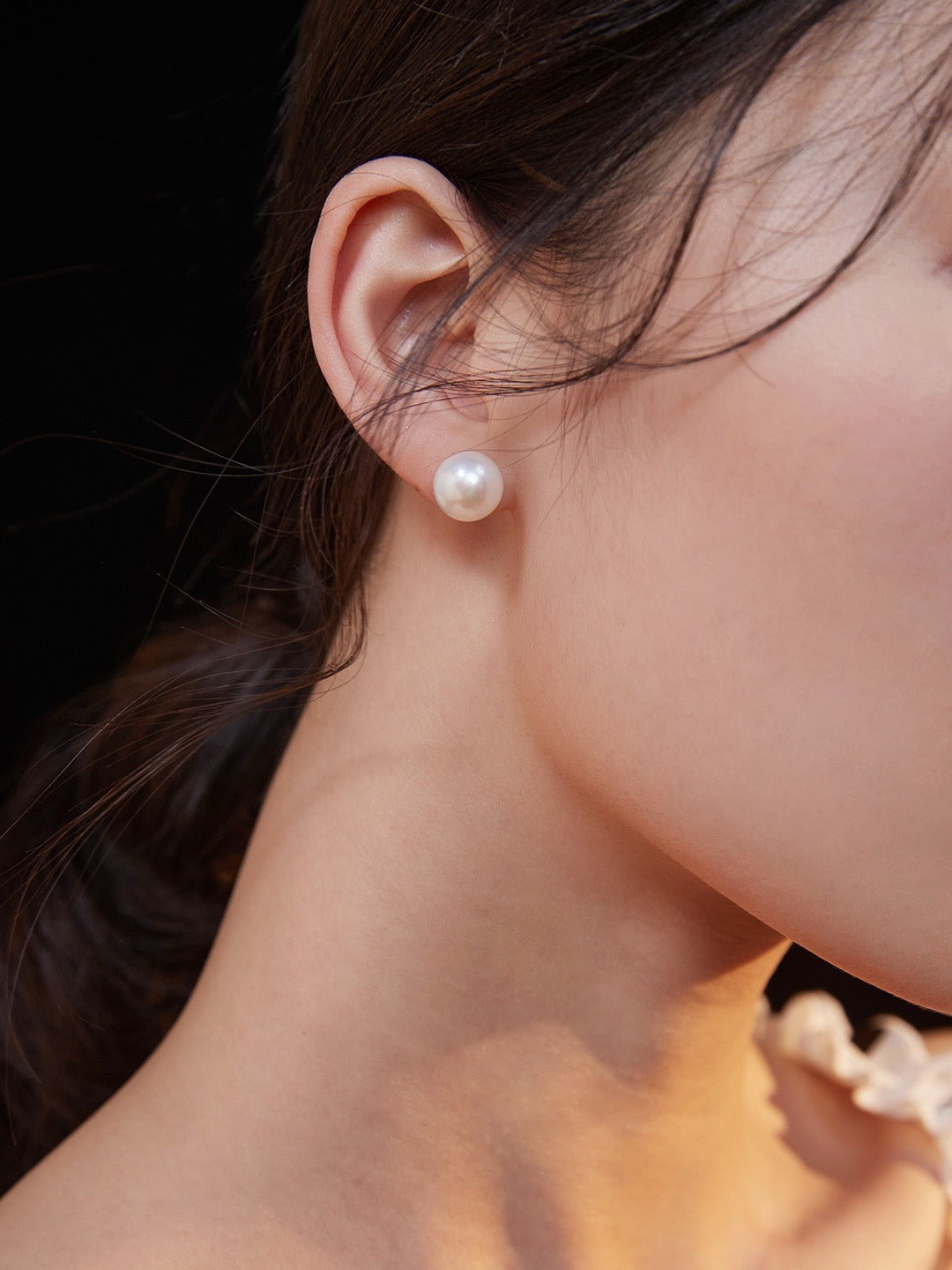 Close-up of a person wearing a pearl earring with a blurred background