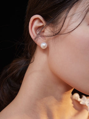 Close-up of a person wearing a pearl earring with a blurred background