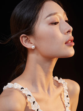 Close-up of a woman wearing a pearl earring with a dark background