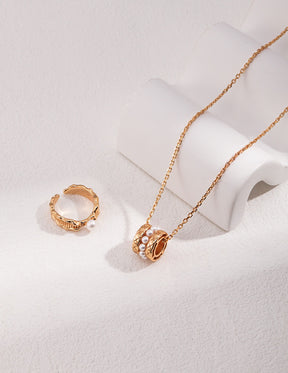 Gold necklace and ring on a light gray background