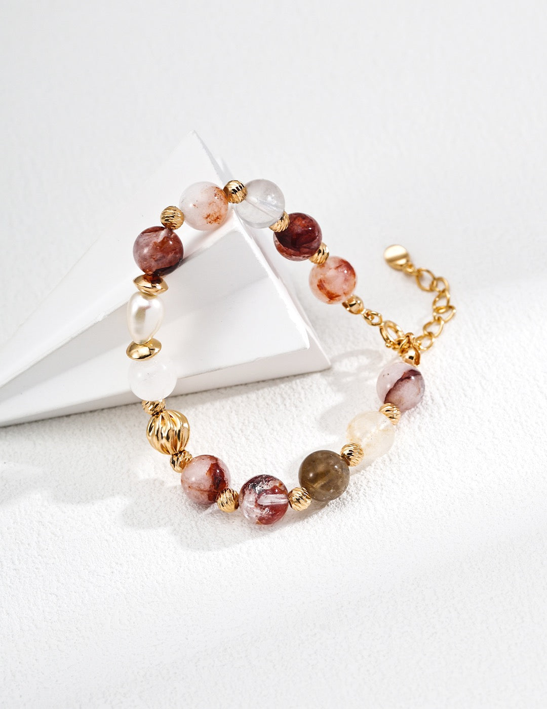 Beaded gemstones bracelet with gold accents on a white surface