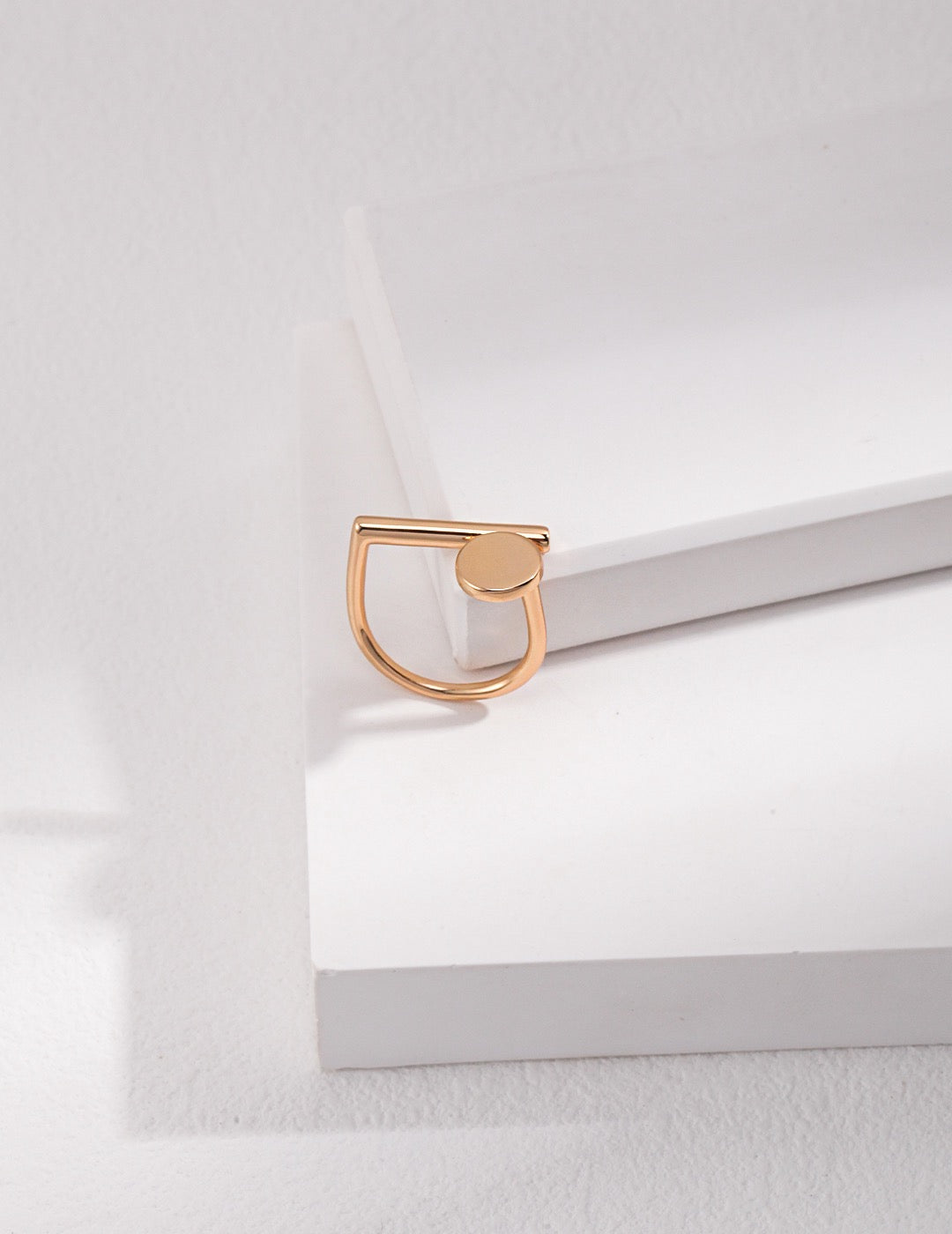 A gold geometry Open Ring displayed on the white rock.