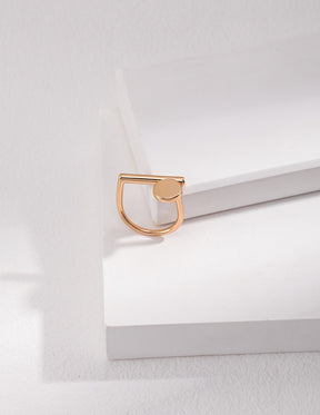 A gold geometry Open Ring displayed on the white rock.
