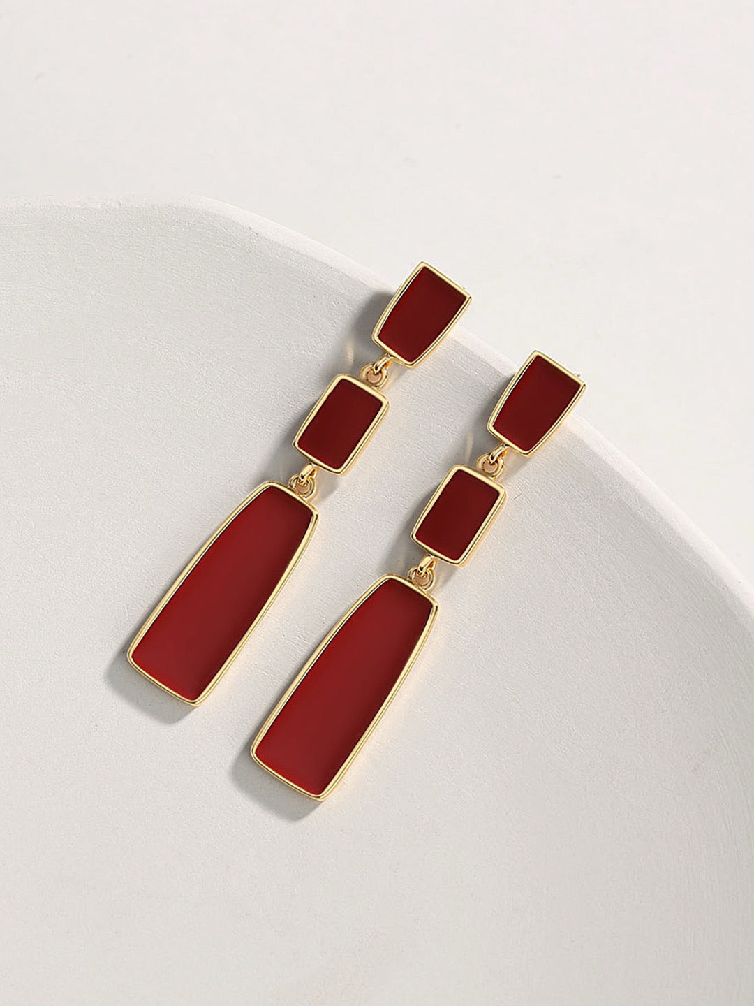 Red earrings with gold accents on a white background