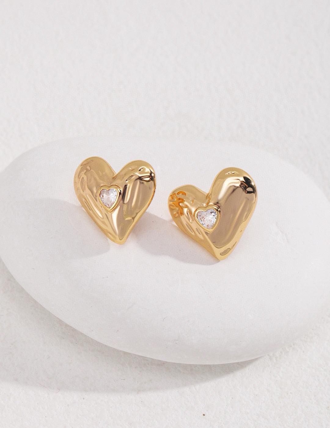 Gold Zircon Heart Shape Stud Earrings displayed on a white rock, showcasing the inlay zircon details.
